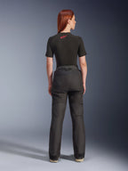 Rear view of a model wearing Alpinestars Stella Andes V4 Drystar® Pants in Black, paired with a black short-sleeve base layer featuring a red Alpinestars logo, adventure-touring motorcycle gear with durable textile construction.