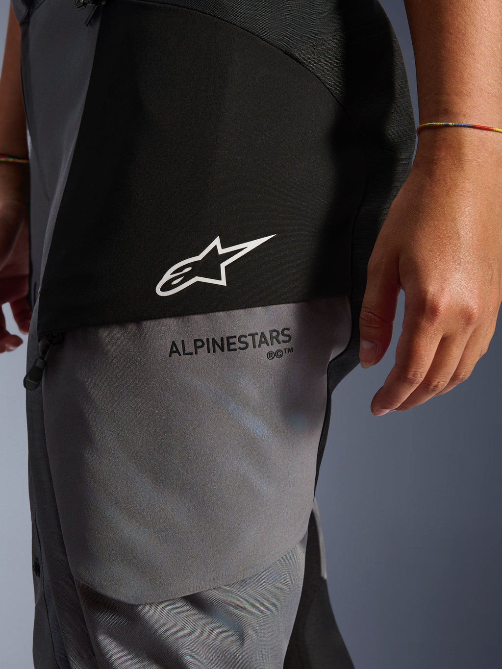 Woman Stella Andes V4 Drystar® Pants, Black and Dark Gray, close-up of the upper thigh showing white star logo and black Alpinestars branding, durable adventure touring textile material