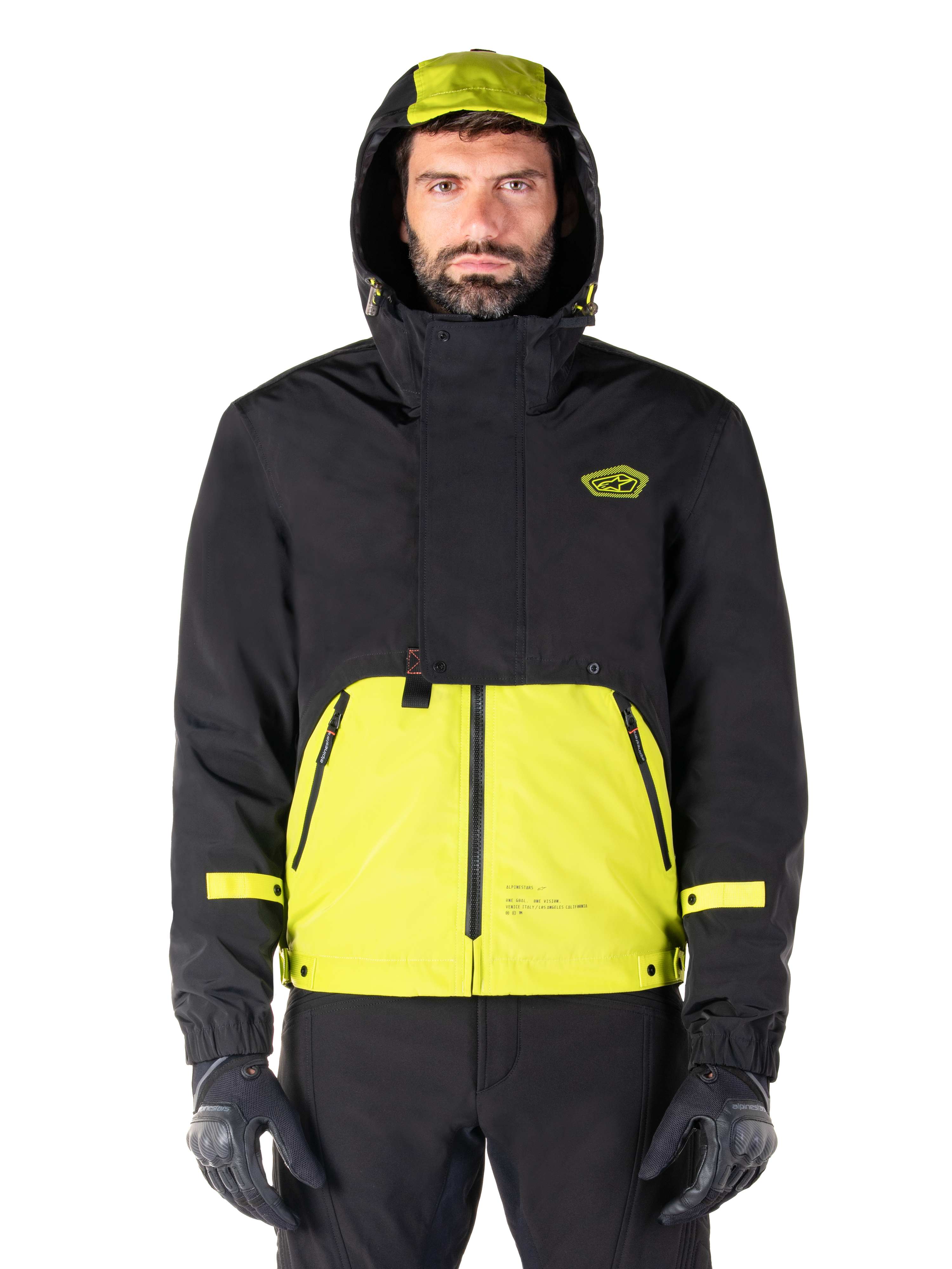 Alpinestars Mootant Waterproof Parka, Lime Punch Black motorcycle jacket, front view, modular 3-in-1 design with black upper and bright lime green lower section, featuring a drawstring hood and chest logo, worn with black pants and riding gloves