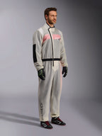 Alpinestars Kart Rain Suit, Clear waterproof karting oversuit, semi-transparent material showing a pink and white racing suit underneath, featuring a black asymmetric zipper, reinforced elbow patch, and black waist band, worn with black karting gloves and racing shoes.