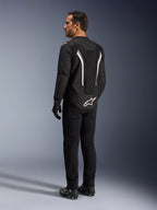 Alpinestars AST V3 Air Jacket, Black and White motorcycle jacket, back view on model, featuring mesh inserts for airflow and white logo on the lower back, worn with black technical riding gear