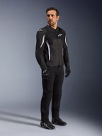Alpinestars AST V3 Air Jacket, Black with white accents and branding, lightweight motorcycle jacket with mesh ventilation, worn by a man with black riding pants, gloves, and shoes, technical summer riding gear for sport and street.