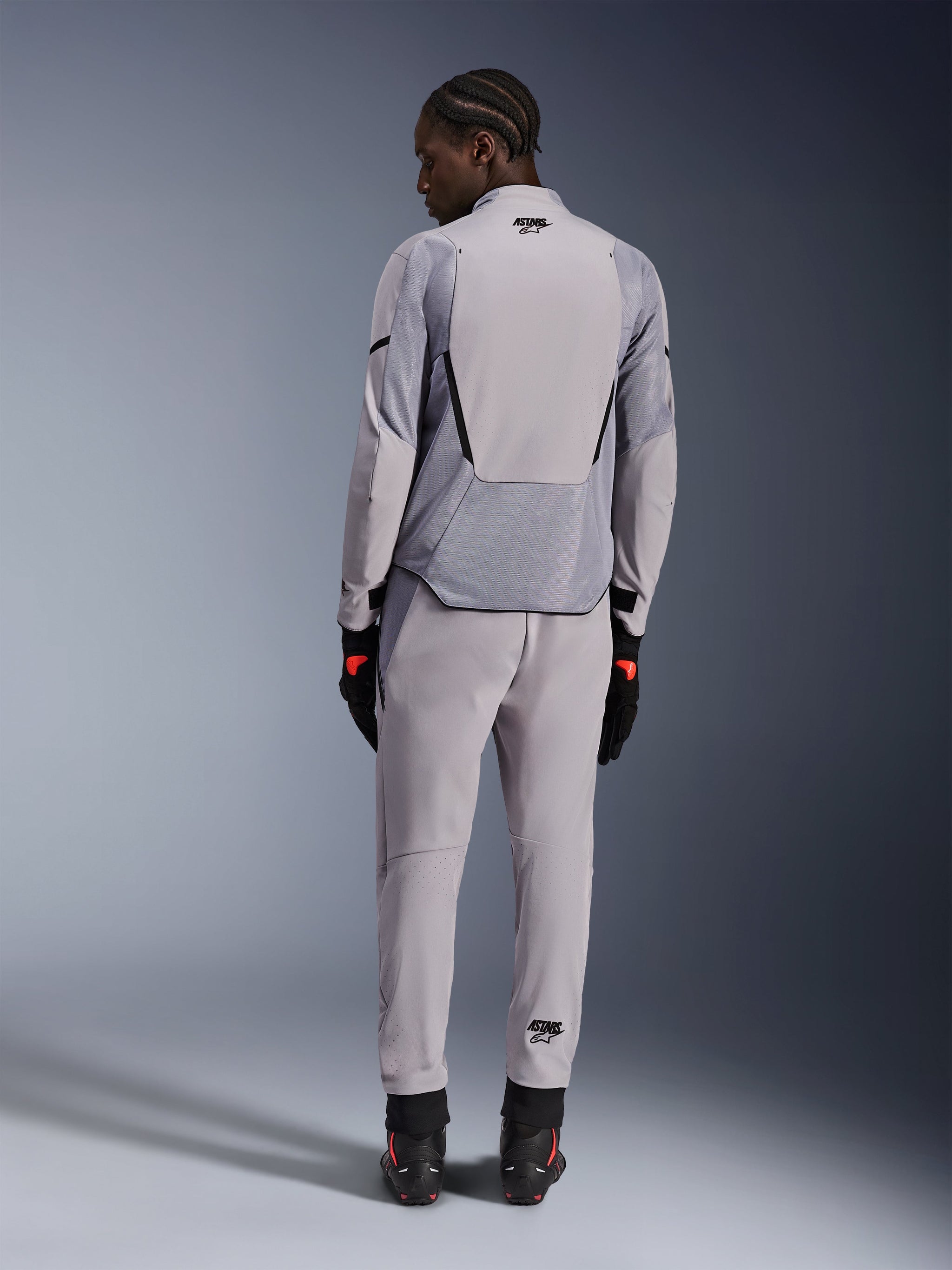 Alpinestars Aeroshell Airflow Jacket, Mid Gray Anthracite, back view on a model, featuring technical mesh panels and laser-perforated ventilation zones, worn with matching gray pants and black motorcycle gear, sport-cut design for high performance.