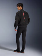 Male model wearing Alpinestars Flight Air Jacket in Black Bright Red, rear view showing vertical red branding on back and 3D mesh construction, paired with black pants and sneakers, urban motorcycle style