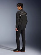 Alpinestars Unite Jacket, Urban Motorcycle Jacket, Black and Dark Gray, back view showing large outlined Alpinestars logo, reflective piping and panels, minimalist softshell design, worn with black pants and casual footwear