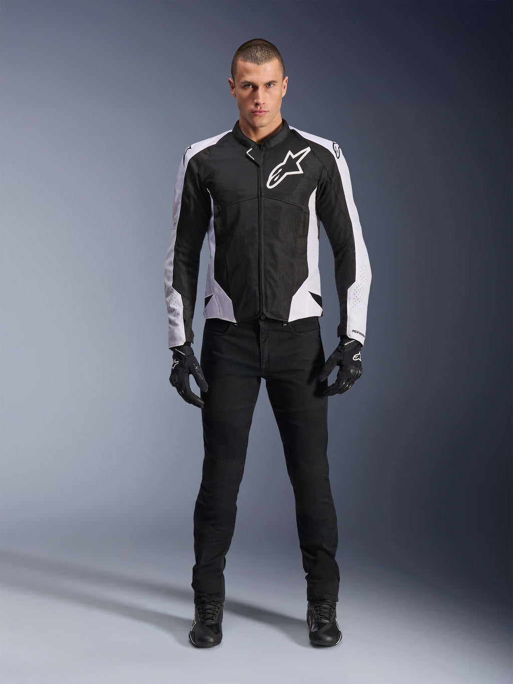 Alpinestars Viper Air V4 Jacket, Black and White motorcycle jacket with large white logo on chest, worn by a male model with black pants and gloves, featuring mesh panels for ventilation, sporty road riding apparel