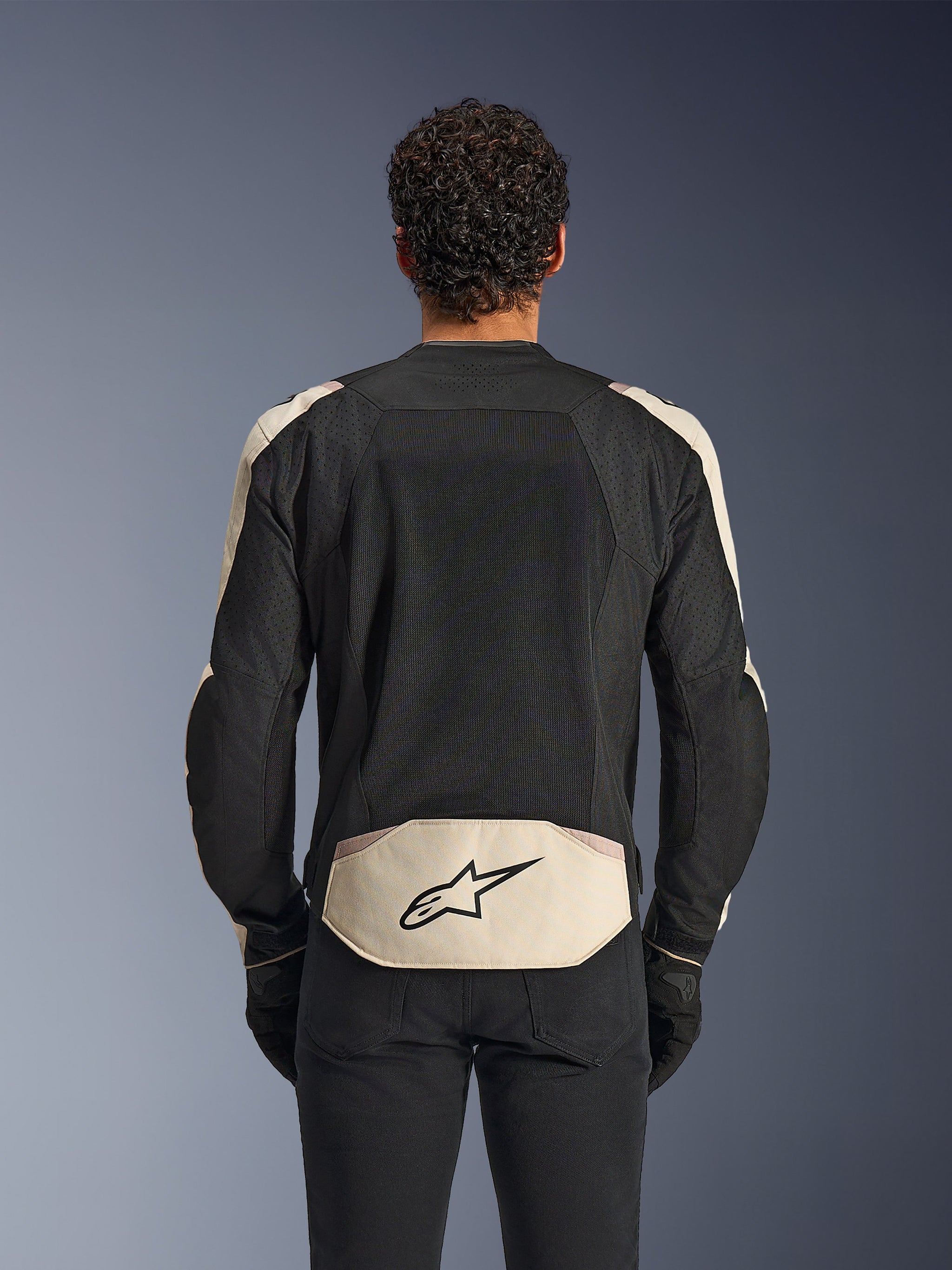 Alpinestars T-SPS Air V2 Jacket, Textile Motorcycle Jacket, Black Mastic Aluminum, rear view showing large mesh ventilation panels on the back, mastic-colored lower panel with black star logo, worn with black pants and gloves, sporty urban design optimized for airflow