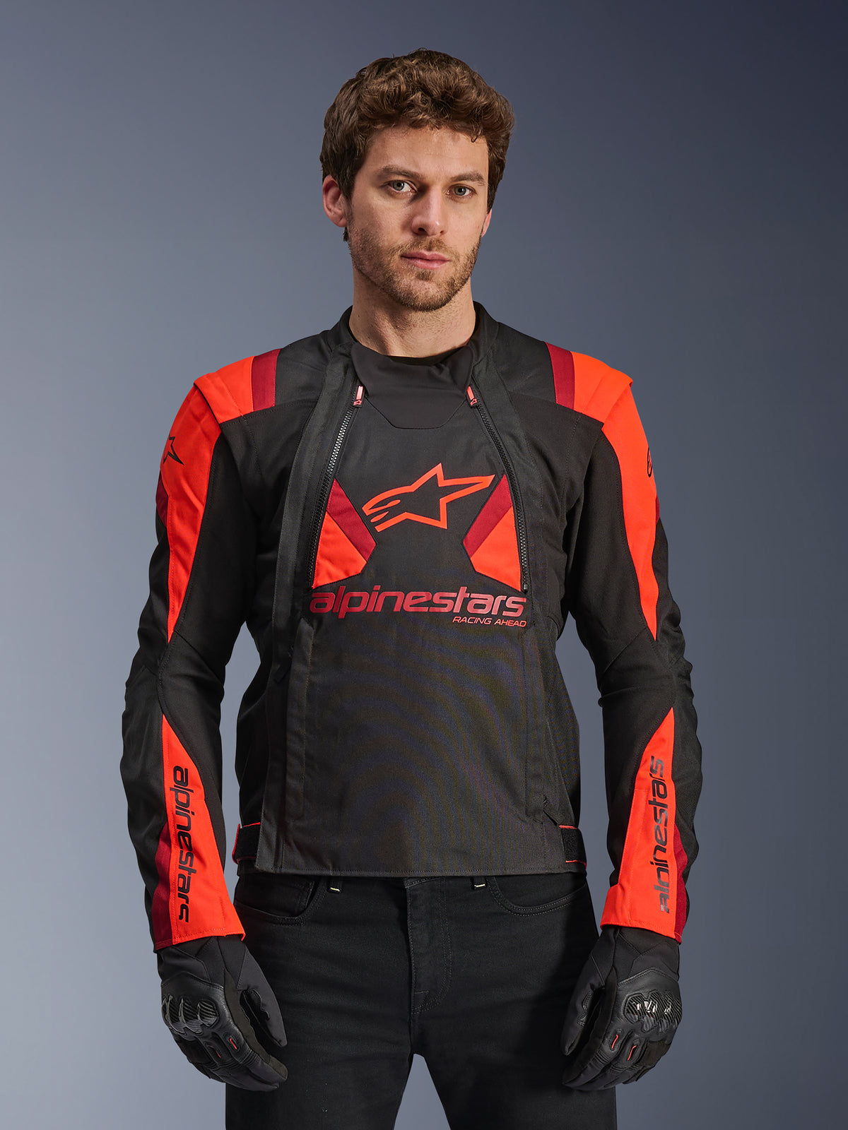 Alpinestars T-Stunt Air Jacket, Textile Motorcycle Jacket, Black Red Fluo and Dark Red, featuring large star logo and mesh panels for airflow, worn by model with black gloves