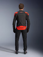 Alpinestars T-Stunt Air Jacket, Black with Red Fluo and Dark Red accents, rear view on model, paired with black riding pants and boots, featuring bold Alpinestars branding on the lower back panel, modular design with mesh construction for ventilation.