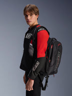 Alpinestars MM93 City Hunter V2 Backpack, Black with red accents, worn by a model in a matching black and red MM93 motorcycle jacket, featuring Marc Márquez branding and logos, urban riding apparel