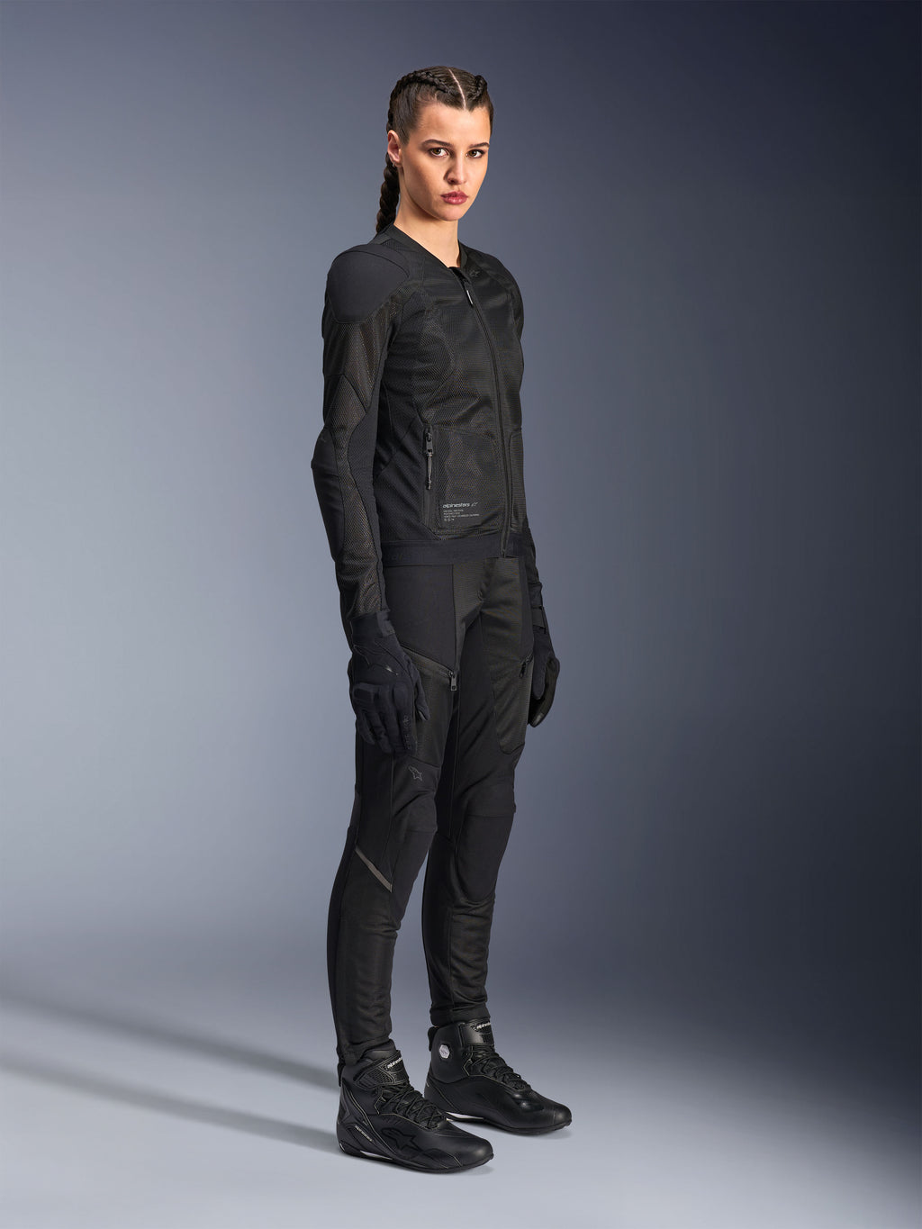 Female rider wearing the Alpinestars Stella Troop-Air Jacket in Black, featuring technical 2D mesh construction, paired with matching black motorcycle pants, gloves, and boots, styled for urban riding.