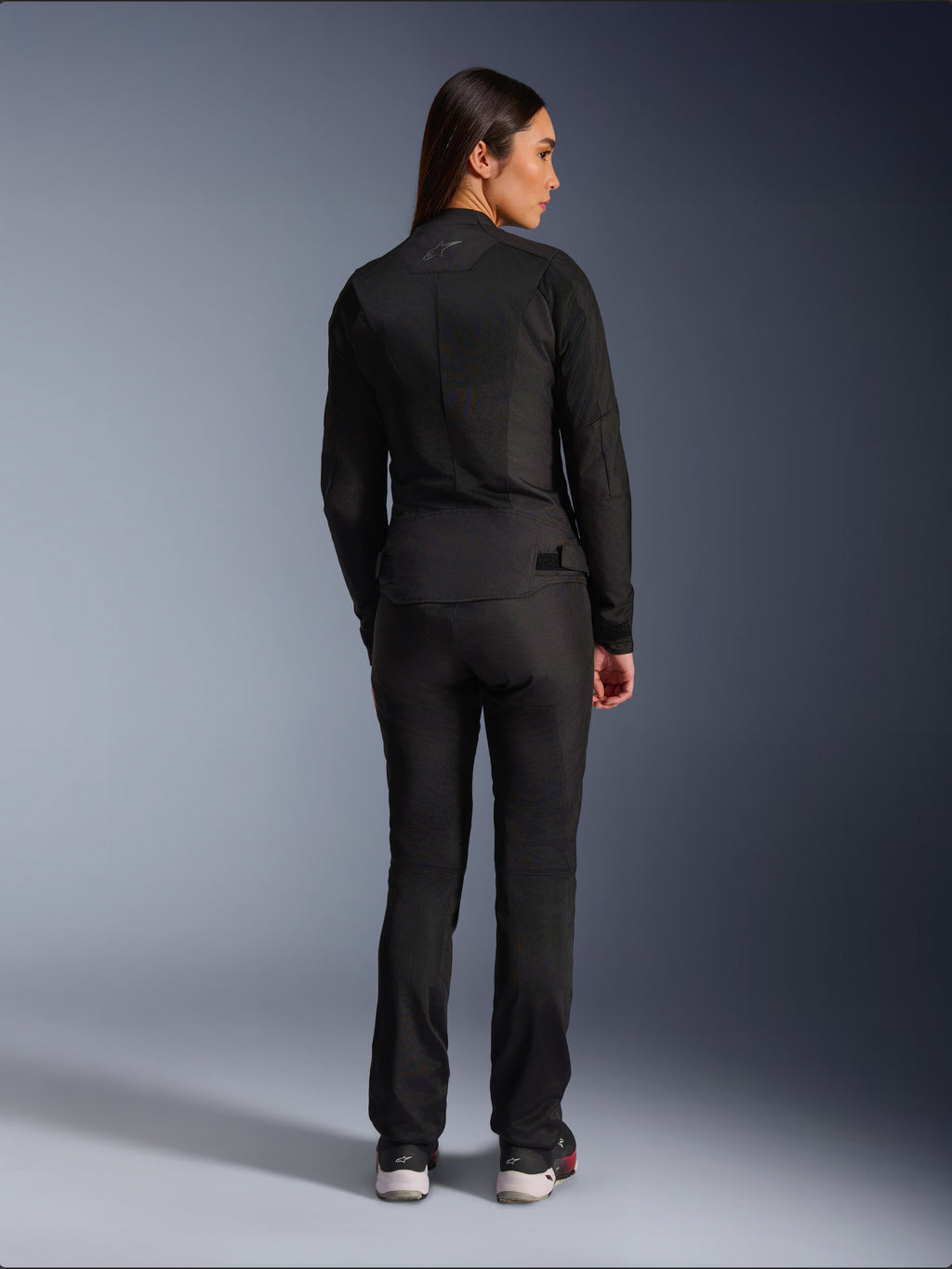 Alpinestars Stella C-1 Air Jacket, Women’s Textile Motorcycle Jacket, Black, rear view showing mesh construction and subtle logo on the upper back, worn with matching black riding pants, urban contemporary style
