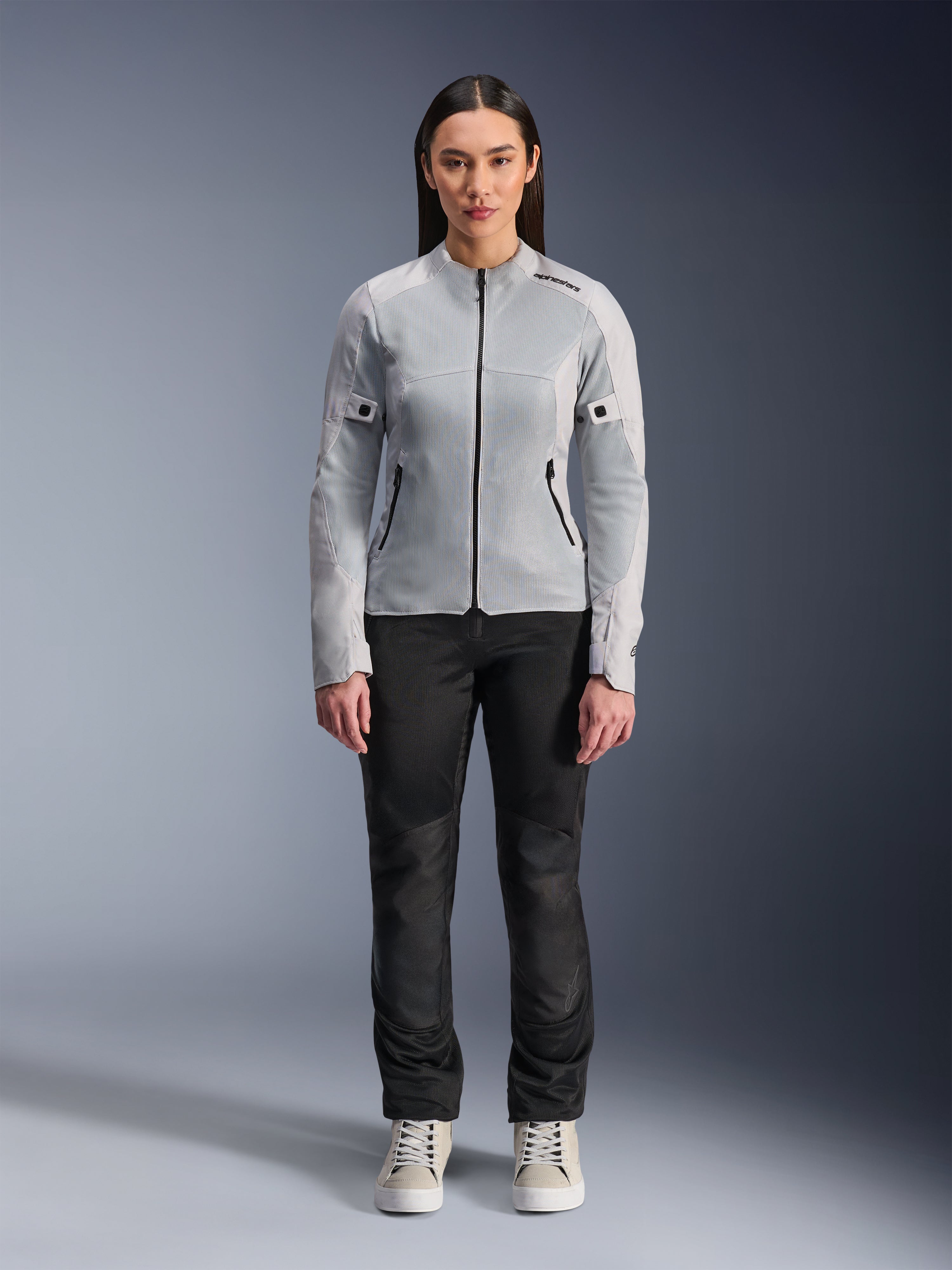 Woman wearing Alpinestars Stella C-1 Air Jacket in Silver, front view, urban motorcycle textile jacket with tech mesh panels, styled with black pants and white sneakers, contemporary riding gear