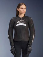 Alpinestars Stella T-GP Plus R V4 Airflow Jacket, Women's Motorcycle Racing Jacket, Black with White and Gray Accents, Textured Mesh Design, Logo on Chest and Sleeves, Worn with Matching Black and White Gloves