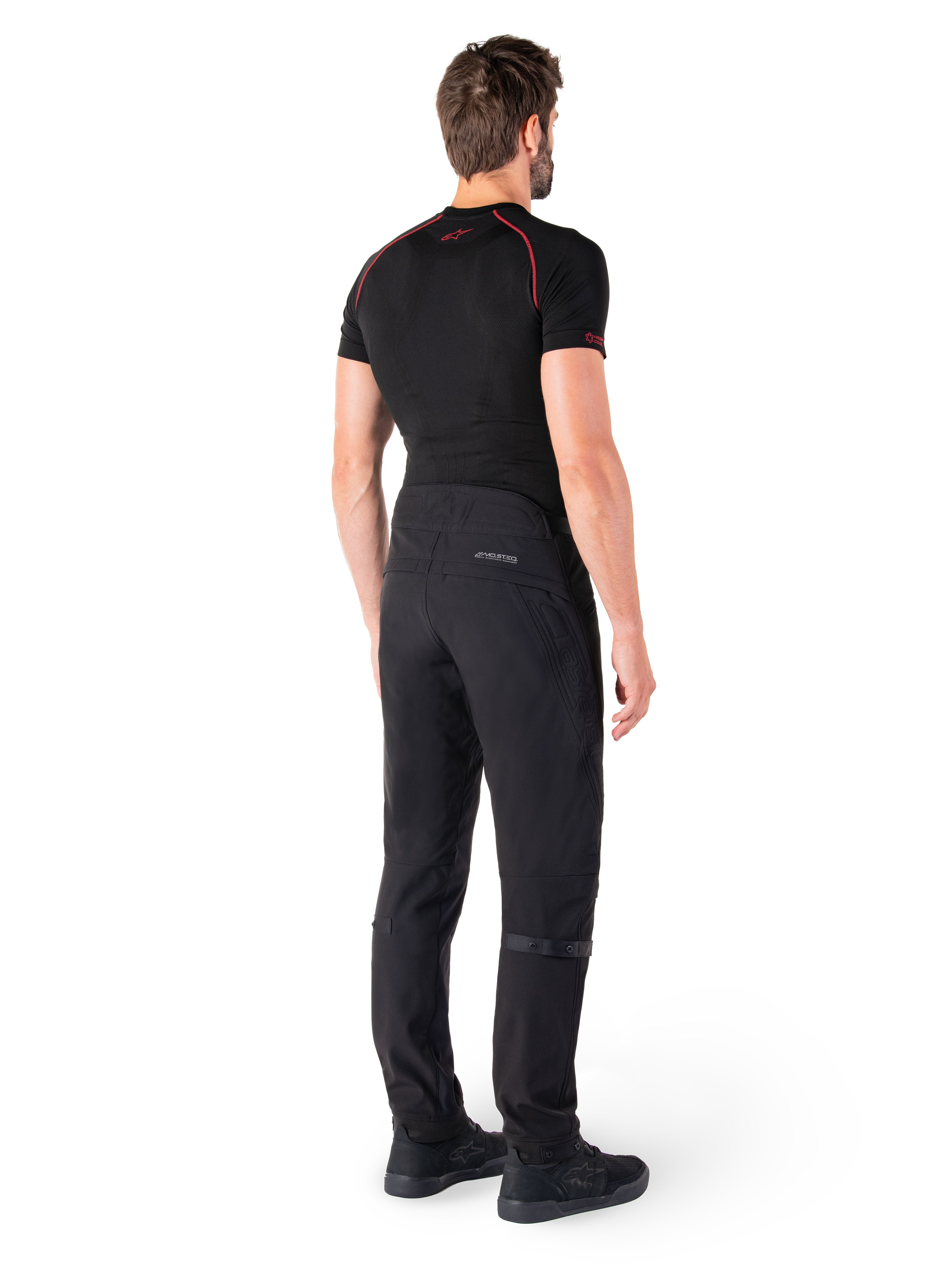 Alpinestars Alden Pants, Black, urban motorcycle pants shown from the back on a model, worn with a black short-sleeve base layer and black riding shoes, featuring quilted detailing and reflective MO.ST.EQ. branding on the back yoke.