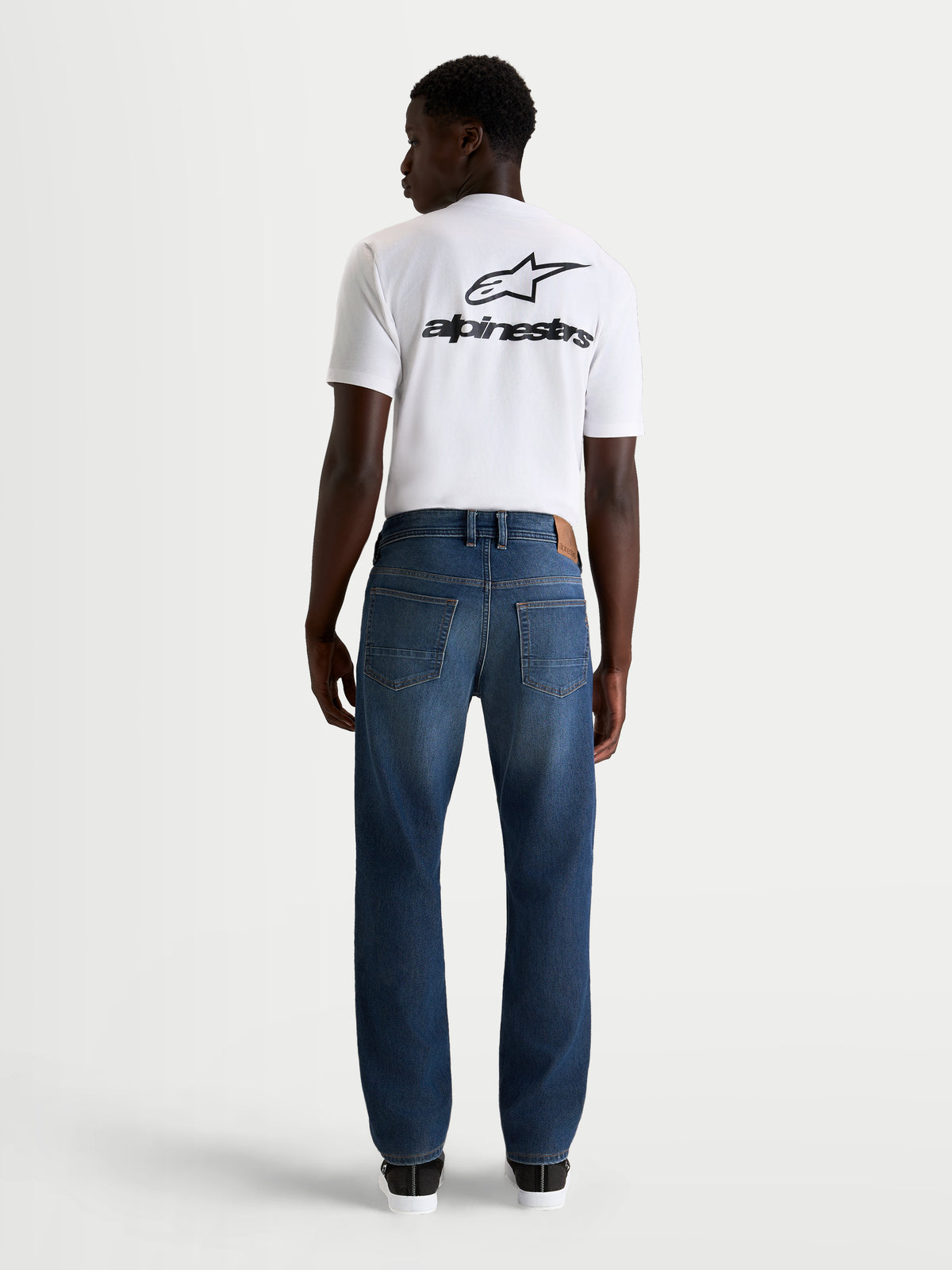Alpinestars Flex-AST 8 Denim Pants, men's urban motorcycle riding jeans in medium blue, rear view showing single-layer technical denim construction and classic five-pocket styling worn by a model.