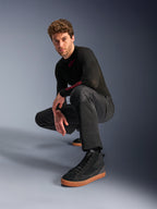 Alpinestars C-1 Air Pants, Urban Motorcycle Pants, Black, model crouching in a studio setting, worn with a black long-sleeve top and black sneakers with tan soles, featuring breathable mesh panels and a contemporary urban style