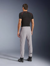 Rear view of a model wearing Alpinestars Aeroshell Airflow Pants in Mid Gray, paired with a black base layer shirt and black shoes, highlighting the laser-perforated zones on the calves and the athletic sport fit.