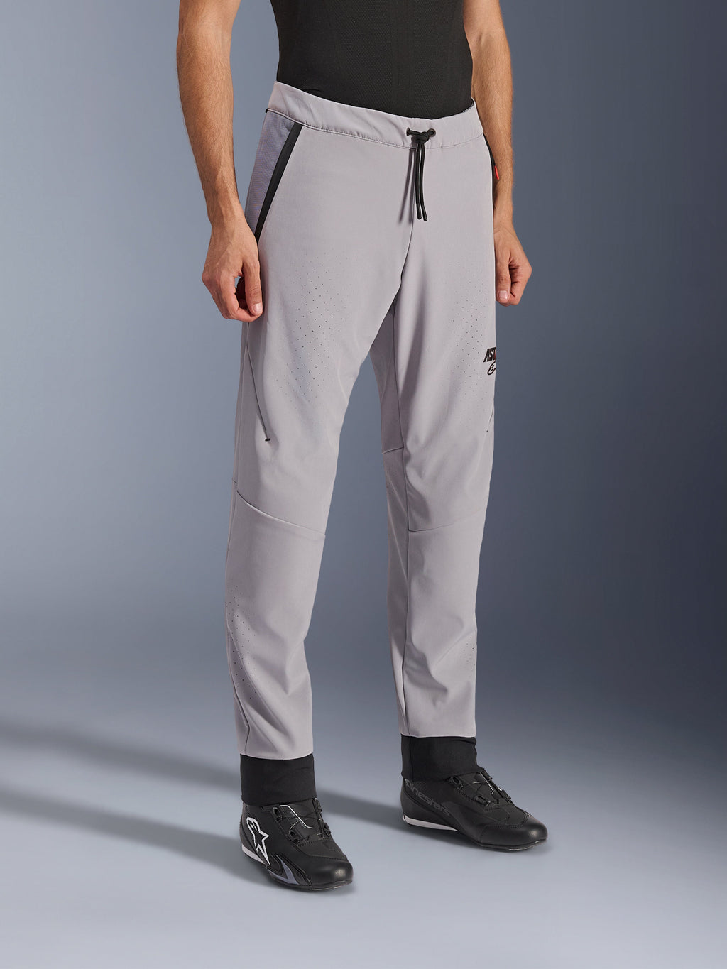 Alpinestars Aeroshell Airflow Pants, Mid Gray, lightweight motorcycle pants with laser-perforated ventilation zones on the thighs and shins, featuring a drawstring elastic waistband and a slim sport fit, styled on a model wearing black riding shoes.