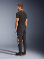 Alpinestars Flex-AST Canvas Pants, Black Aluminum, Urban Motorcycle Pants, featuring tan side panels with Alpinestars branding, worn with a black base layer and sneakers, back view showing workwear-inspired styling and ergonomic moto fit.