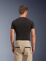 Alpinestars Flex-AST Canvas Pants in brown, rear view showing zippered back pockets and workwear-inspired hammer loop, worn with a black short-sleeve base layer featuring red contrast stitching, urban motorcycle riding apparel
