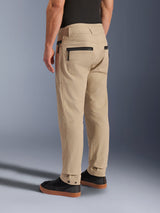 Alpinestars Flex-AST Canvas Pants, Brown, rear view of urban motorcycle pants featuring workwear-inspired design with black zippered pockets and snap button ankle adjustments, worn with black sneakers.