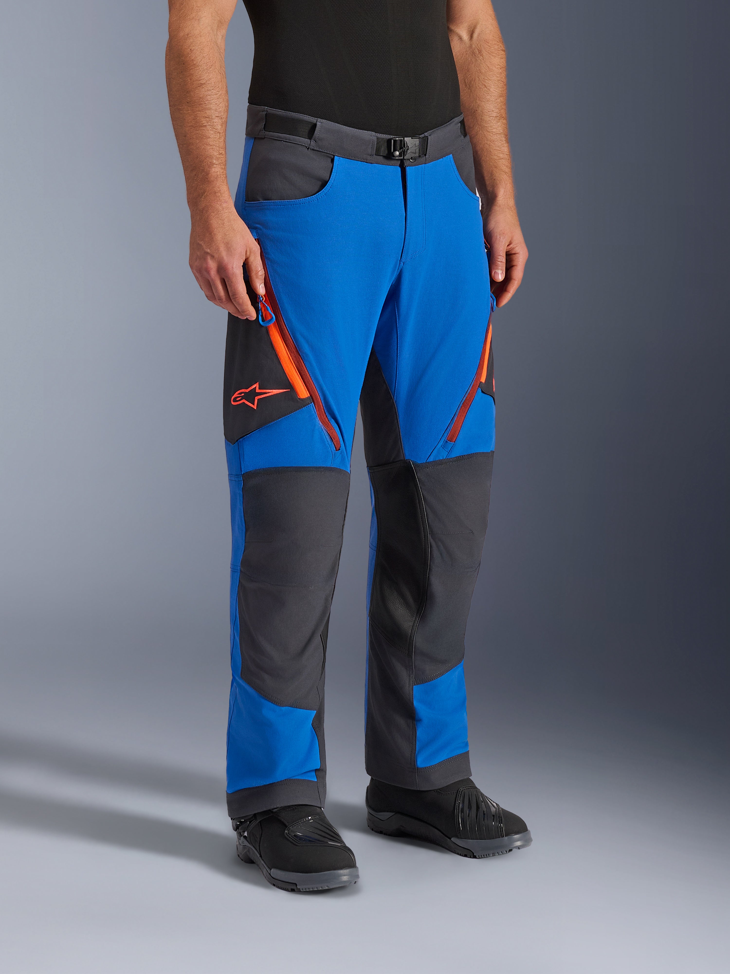 Alpinestars Maxdura Dual Pants, adventure motorcycle pants, Royal Blue and Deep Gray with orange accents, featuring zippered thigh vents, reinforced knee panels, and a magnetic buckle belt, technical over-boot design for dual-sport riding.