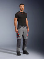 Alpinestars Maxdura Dual Pants, Adventure Motorcycle Pants, Dark Gray and Deep Gray, worn with a black base layer and boots, featuring red zippered vents, reinforced panels on knees and seat, and a belted waist, athletic fit for dual-sport riding
