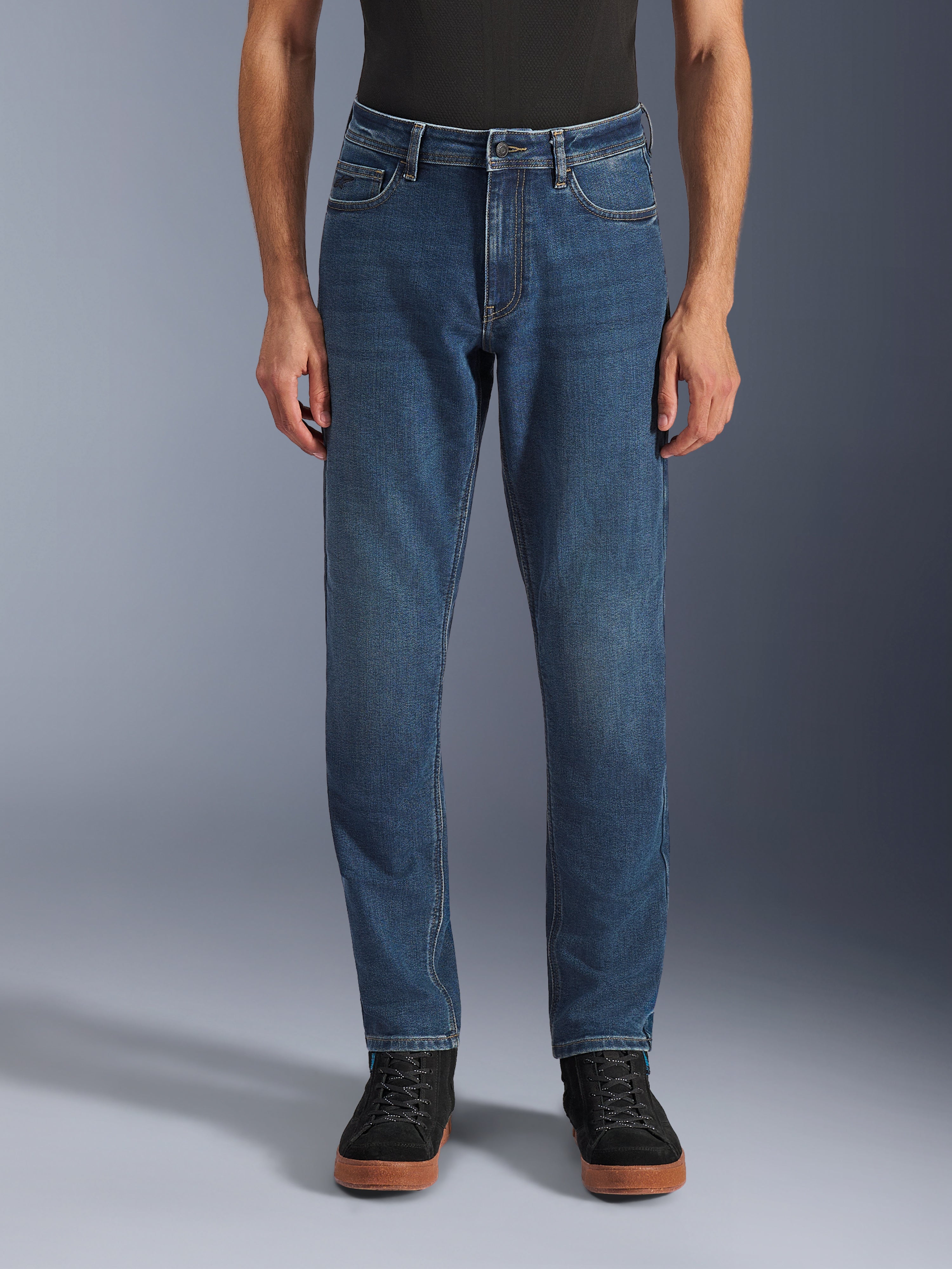 Alpinestars Flex-AST 5 Denim Pants, Urban Motorcycle Jeans, Indigo Washed Blue, front view showing a modern tapered fit and casual five-pocket styling, worn with a black top and sneakers, designed for urban riding comfort and protection.
