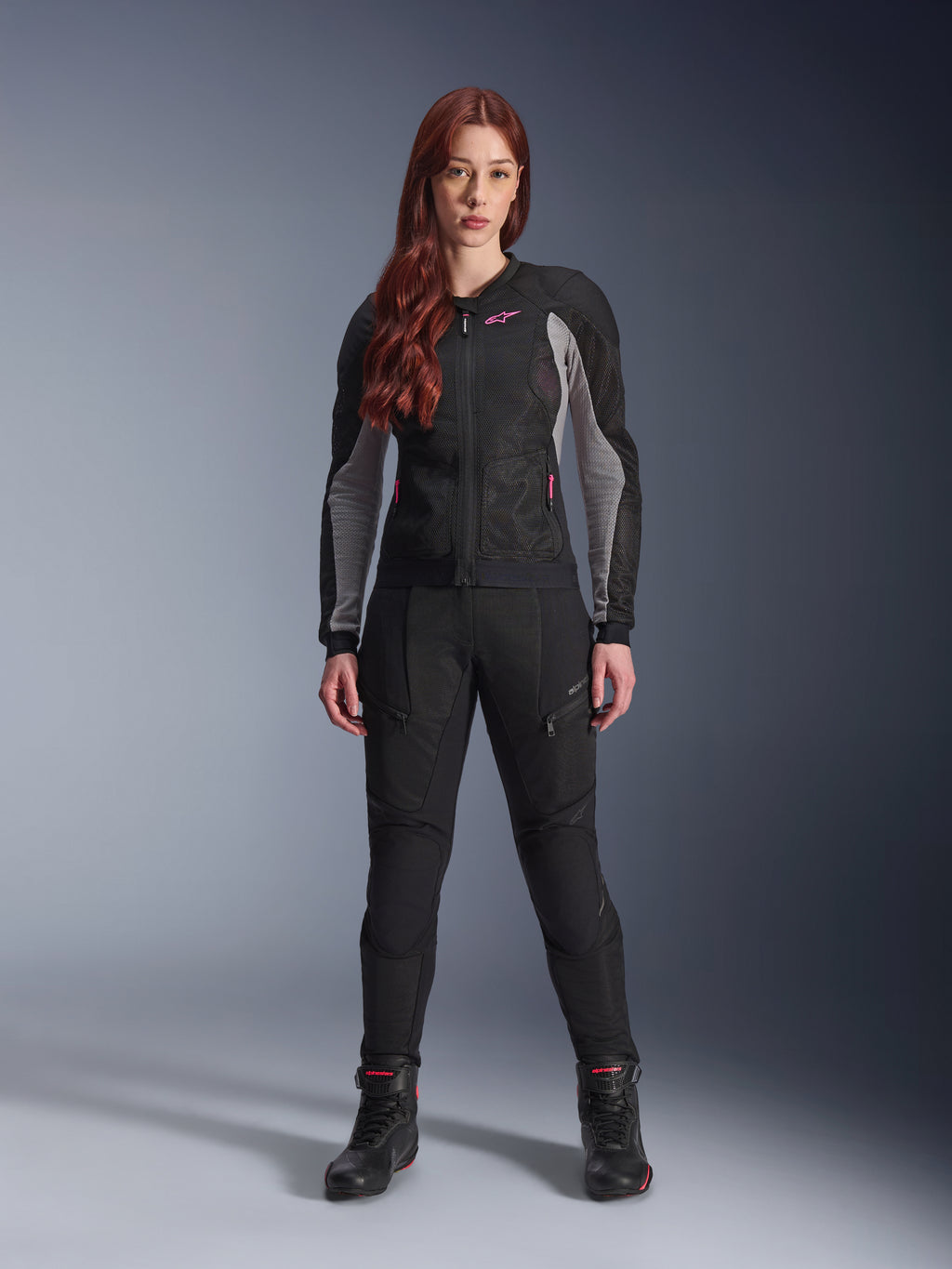 Alpinestars Stella Troop-Air Pants, Women's motorcycle riding pants in black, features mesh panels and zippered pockets, styled with a matching black and grey mesh jacket with pink accents and black riding boots, complete urban motorcycling outfit.