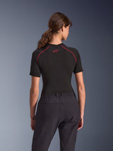 Woman wearing Alpinestars Stella Flex-AST Explorer Pants, Black adventure motorcycle pants, back view, paired with a black short-sleeved top with red stitching, highlighting the breathable textile construction and elastic waistband.