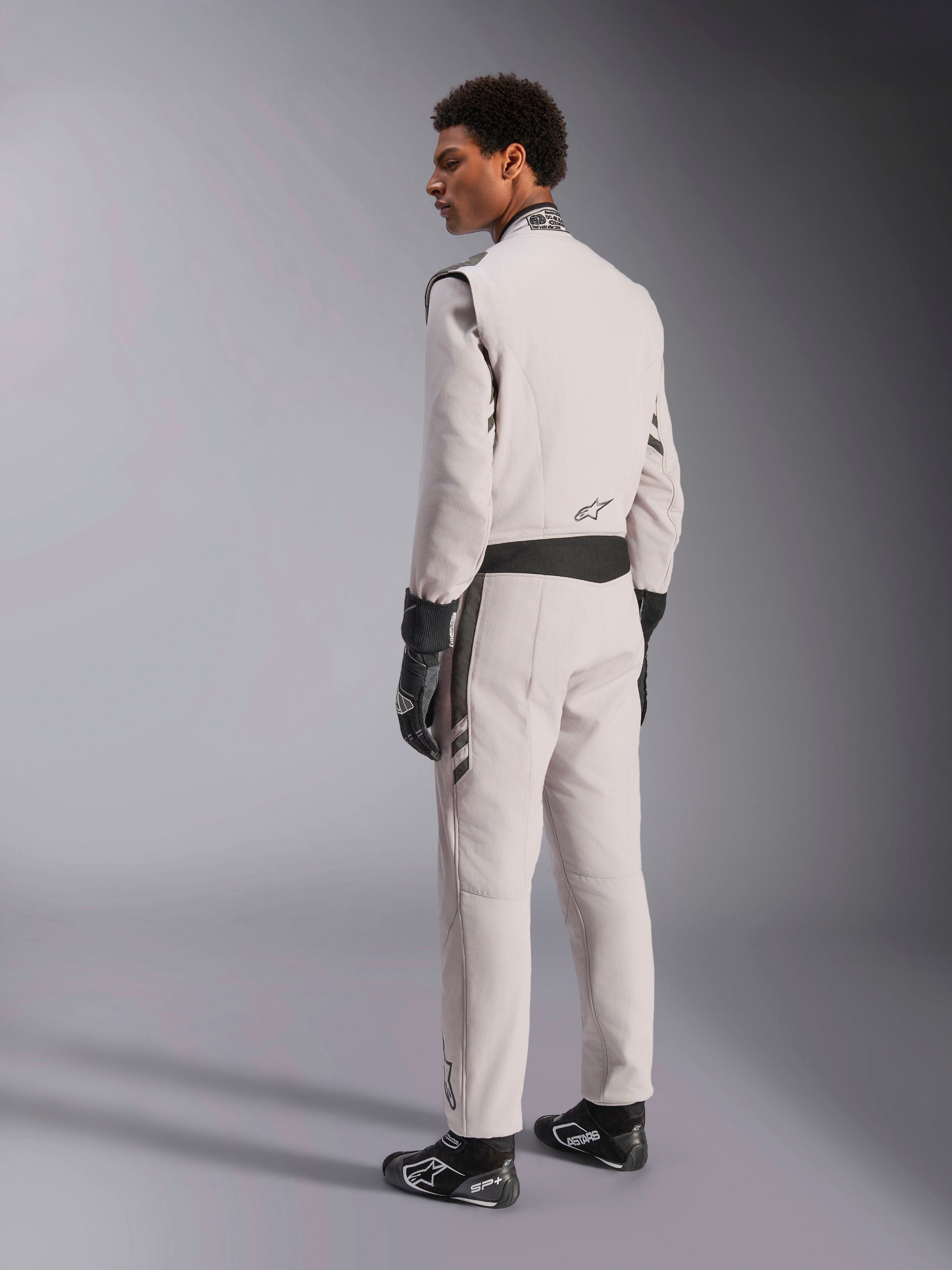 Alpinestars GP Race V3 Suit FIA, Silver Anthracite racing suit, side and back view, worn with black racing gloves and boots, featuring dark gray accents on the waist and shoulders, professional auto racing protective apparel.