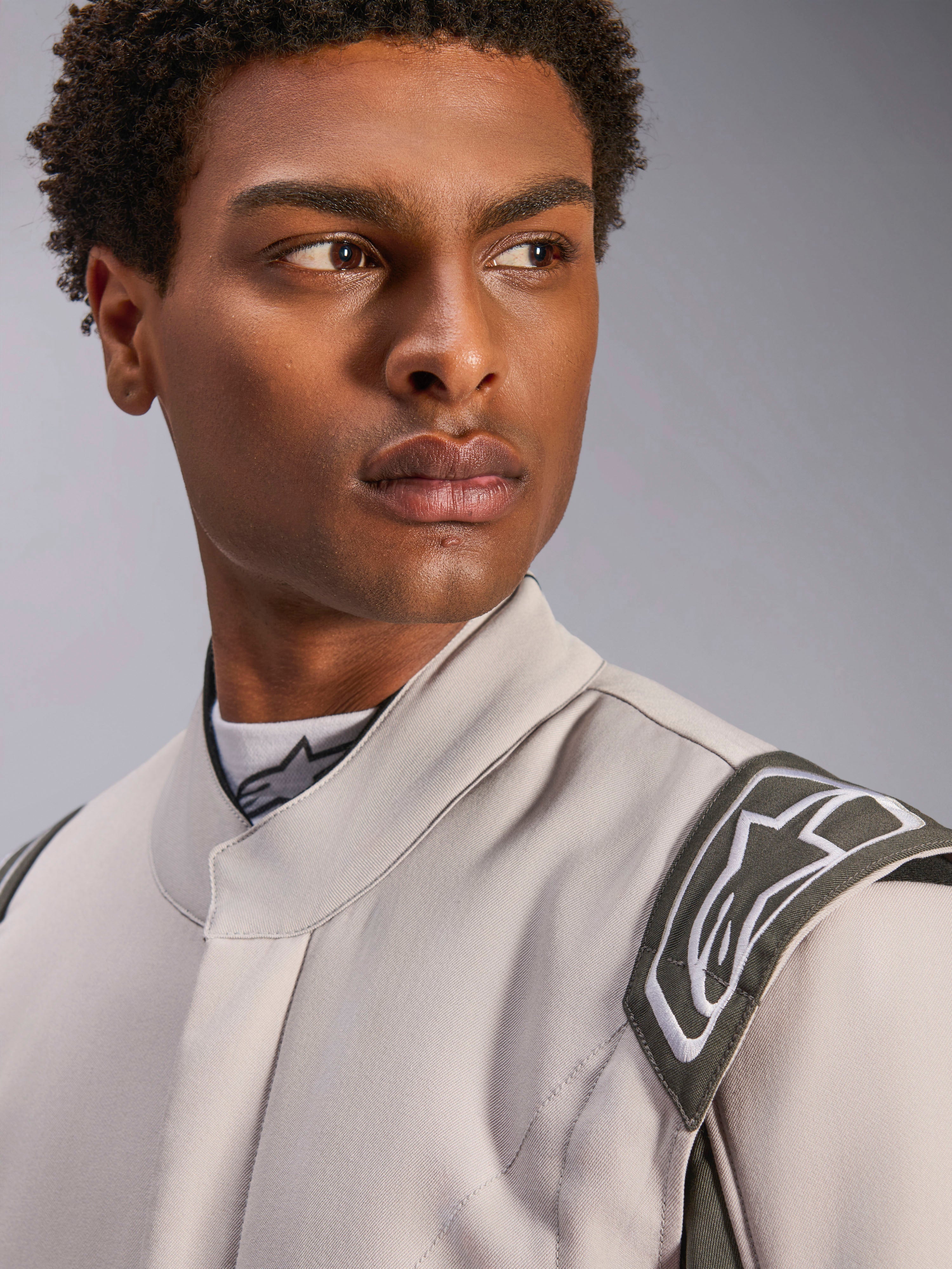 Model wearing the Alpinestars GP Race V3 Suit FIA in Silver Anthracite, close-up shot focusing on the upper torso and shoulder, showcasing the extraction epaulette and ergonomic collar, professional auto racing gear