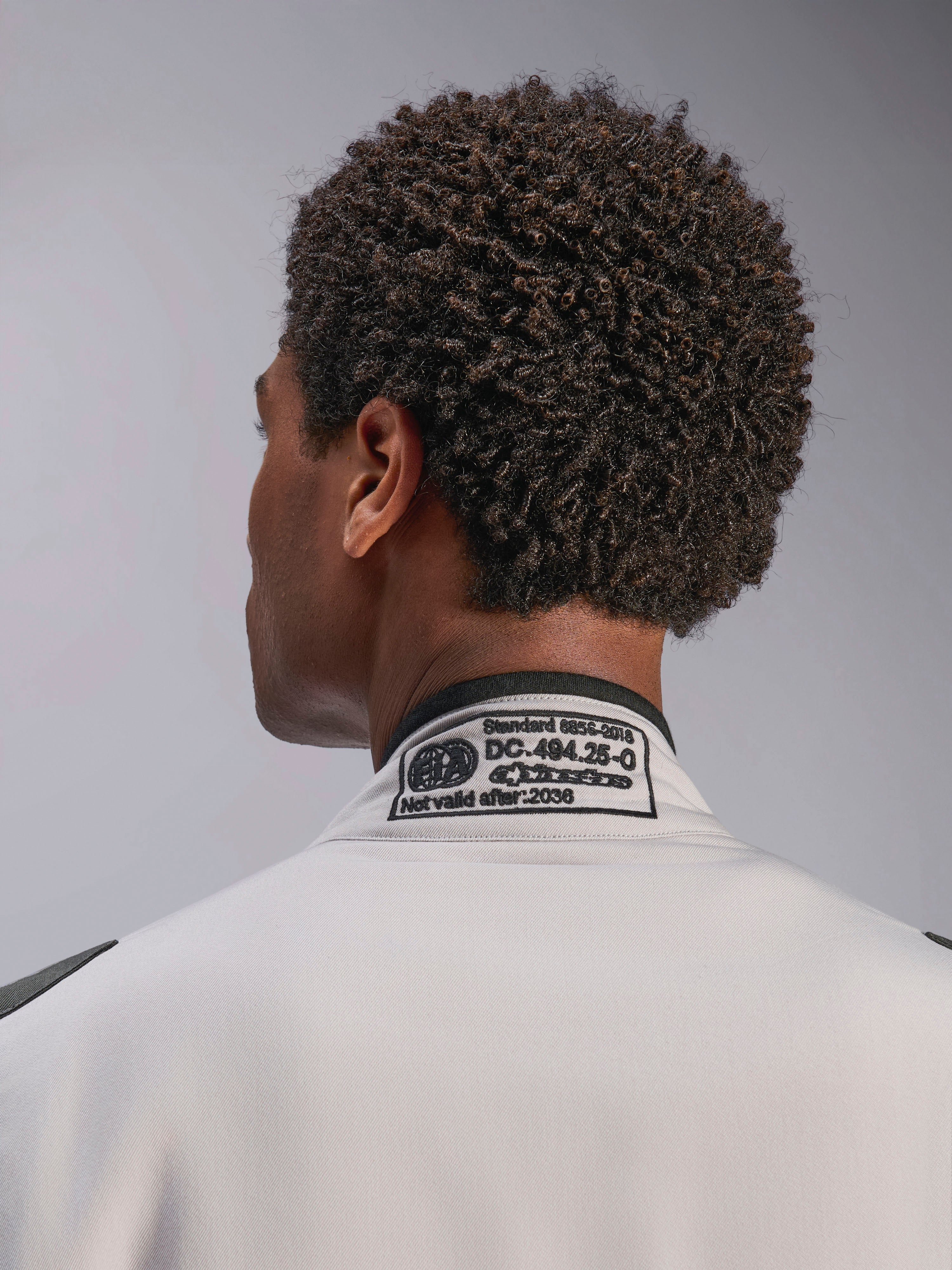 Alpinestars GP Race V3 Suit FIA, Silver Anthracite, close-up of the back collar featuring the embroidered FIA 8856-2018 certification label, detailing safety compliance for auto racing gear