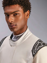 Close-up of a male model wearing the Alpinestars Hypertech V3 Suit in White Black Silver, featuring a high collar with secure closure and Alpinestars logos on the shoulders, professional auto racing gear.