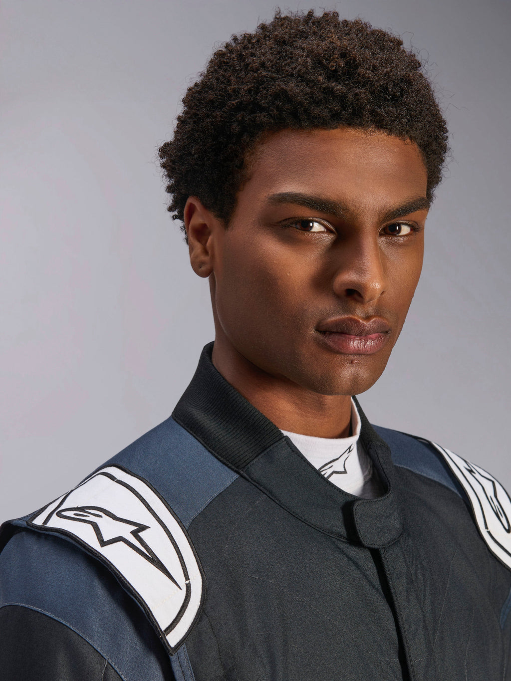 Alpinestars GP Pro Comp V2 FIA Suit, men's auto racing gear in Black and Asphalt with white logo shoulder epaulettes.