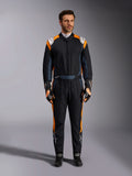 Alpinestars GP Pro Comp V2 FIA Suit, Black Asphalt and Orange Fluo auto racing suit, male model wearing full protective gear with matching racing gloves and shoes, features white Alpinestars logos and vibrant orange side panels, professional motorsport apparel