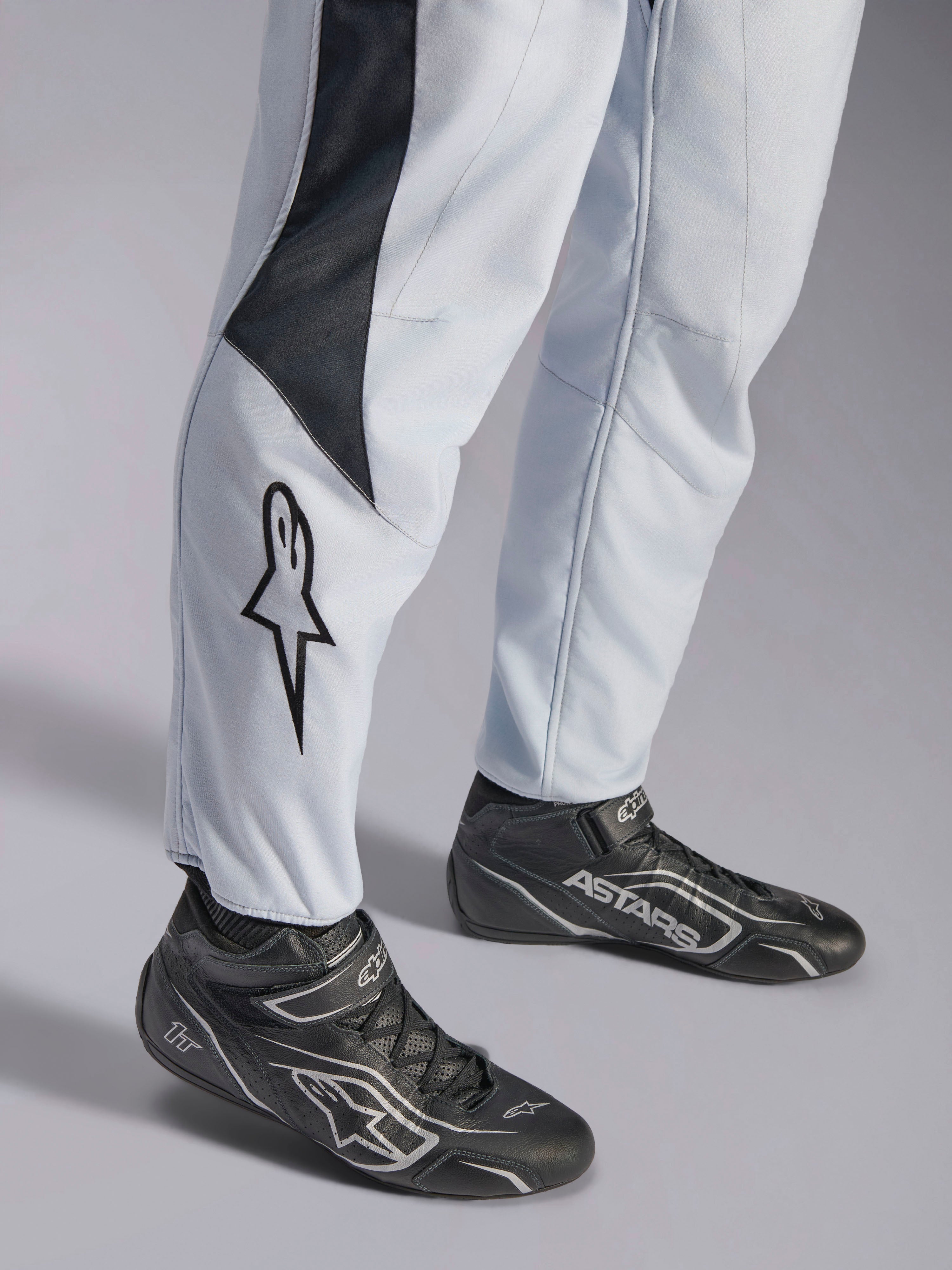 Alpinestars GP Pro Comp V2 FIA Suit, Gray and Black Auto Racing Suit with leg star logo and racing boots.