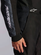 Alpinestars KMX-5 V3 Suit, Karting Suit, Black and Dark Shadow, close-up detail of side hip and arm, white ASTARS branding on the sleeve, white logo on the waist, featuring mesh panels for ventilation and a knitted wrist cuff