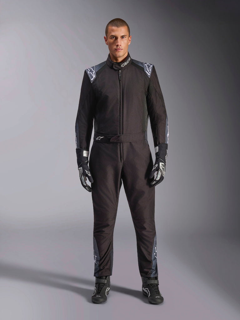 Alpinestars KMX-5 V3 Suit, Karting Suit, Black Dark Shadow, full body view of a model wearing the suit with matching gloves and boots, featuring dark gray accents and white Alpinestars logos on shoulders and belt, professional motorsport racing gear.