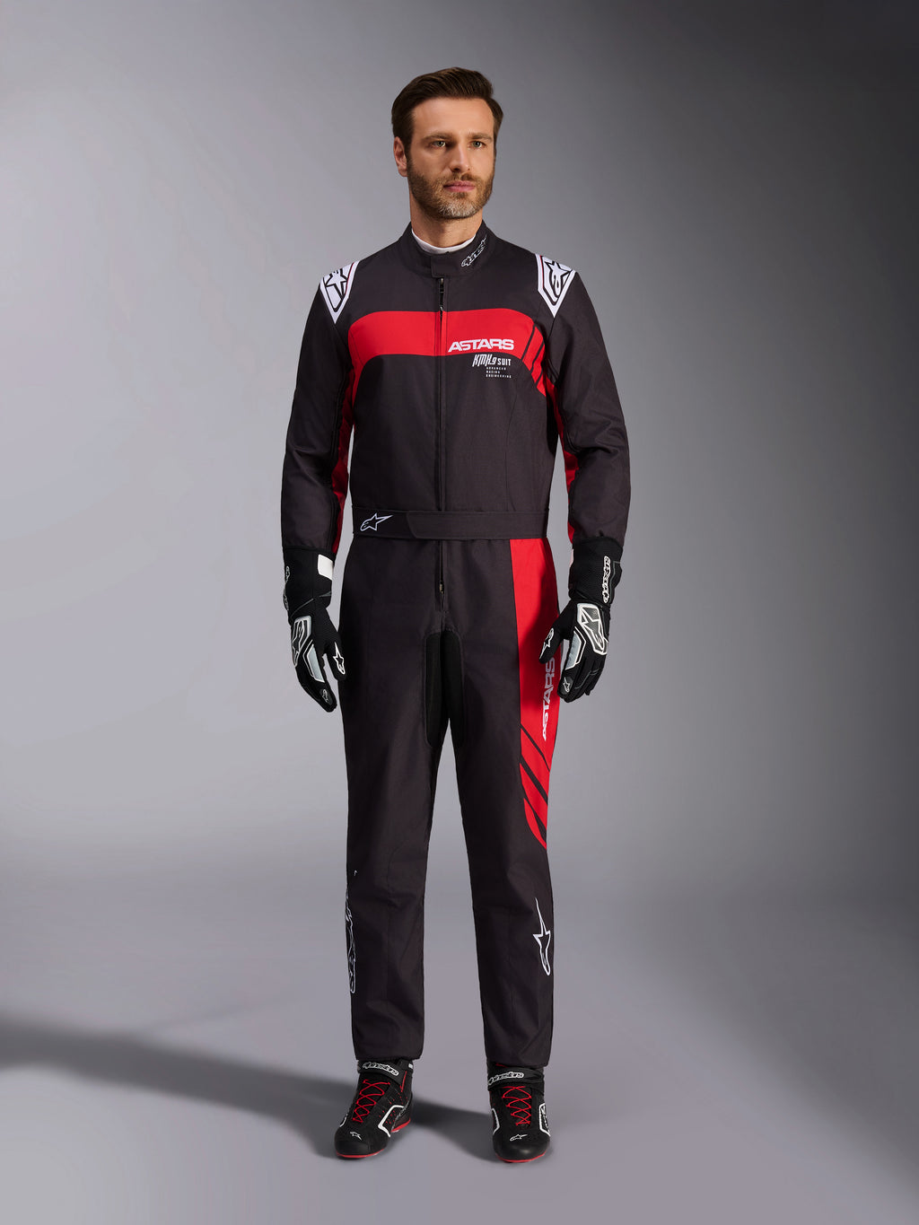 Alpinestars KMX-9 V3 Graphic 3 Suit, Karting Suit, Black and Red, full-body front view worn by a model, featuring bold red graphic panels and white branding, paired with black racing gloves and shoes, professional motorsport apparel.
