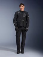 Alpinestars ST-7 2L GORE-TEX Jacket, adventure touring motorcycle jacket, Black and Dark Gray, worn with matching black riding pants and gloves, featuring multiple cargo pockets, reflective accents, and Alpinestars Exploration Equipment chest branding, functional design for road and off-road riding