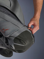 Alpinestars Nazca 3L GORE-TEX PRO Pants, Adventure Motorcycle Pants, Dark Gray and Black, close-up of a hand opening the zippered thigh ventilation intake, featuring textured Superfabric knee reinforcements and a red Alpinestars star logo, technical textile construction for all-weather protection