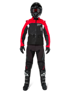 Motocross rider wearing complete off-road gear, Alpinestars Pro-Dura Jacket in Black, Bright Red, and White, black pants with red accents, black helmet with red goggles, black and white boots, coordinated outfit for enduro and trail riding