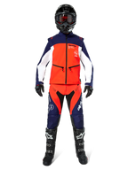 Motocross rider wearing complete off-road gear, Lite-Dura Softshell Jacket in Navy Hot Orange and White, matching navy and orange pants, black helmet with goggles, black and white boots, black gloves, coordinated outfit for enduro racing