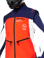 Alpinestars Lite-Dura Softshell Jacket in Navy Hot Orange and White, close-up view of the torso, featuring a bright orange front panel with white side panels and navy blue shoulders, zippered hand pockets, and prominent Alpinestars branding, worn by a rider with a black off-road helmet.