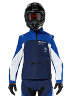 Motocross rider wearing the Alpinestars Lite-Dura Softshell Jacket in Navy Bright Blue White, front view, paired with a black helmet and red-tinted goggles, featuring a technical windproof design with zippered pockets and white accents for off-road enduro riding