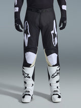 Alpinestars 2026 Racer Air Riway Pants, Motocross Pants, Black and White, featuring bold white Alpinestars logos on the thighs and knee panels, paired with white and black motocross boots and black gloves, athletic race-fit design for off-road riding
