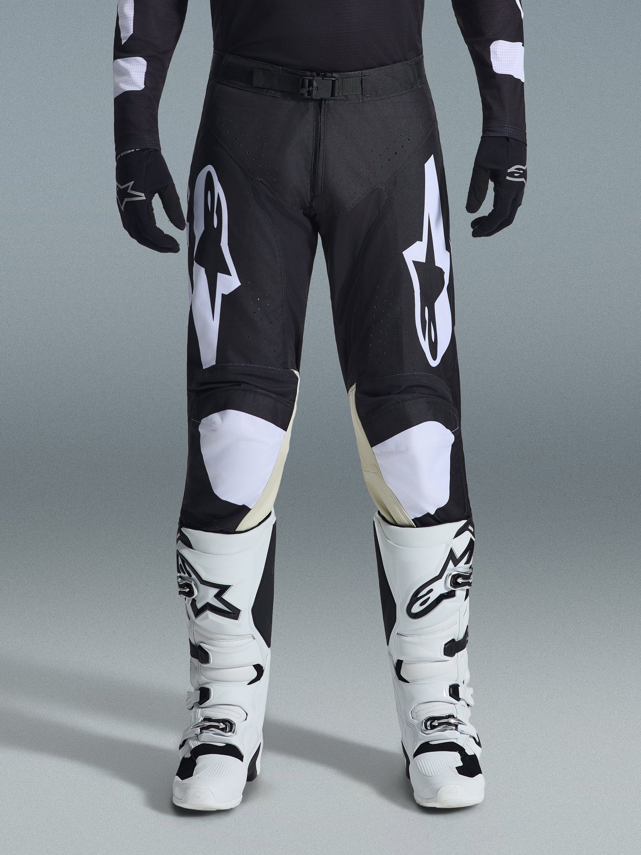 Alpinestars 2026 Racer Air Riway Pants, Motocross Pants, Black and White, featuring bold white Alpinestars logos on the thighs and knee panels, paired with white and black motocross boots and black gloves, athletic race-fit design for off-road riding