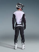 Motocross rider seen from behind wearing Alpinestars 2026 Racer Air Riway Pants in Black and White, matching black and white long-sleeve jersey, white and black racing boots, and a black helmet with Alpinestars branding